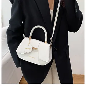 Détail du sac selle blanc avec ferrures dorées et lettrage fashion élégant