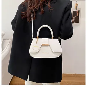 Détails du sac selle blanc porté sur un blazer noir avec des finitions dorées élégantes