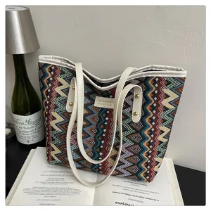 Detail der gewebten Boho-Tasche mit bunten Zickzack-Mustern und weißen Ledergriffen