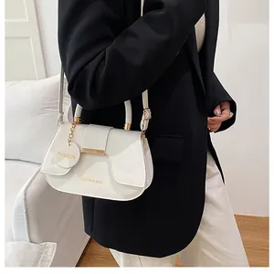 Détail du sac selle en cuir blanc avec finitions dorées et pendentif Fashion chic