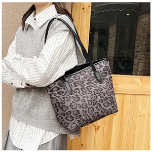 Dettaglio della borsa tote leopardata grigia con manici in pelle nera e bordi rinforzati
