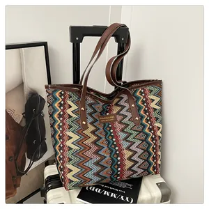 Detail einer bunten gewebten Tasche mit Ledergriff am weißen Koffer hängend