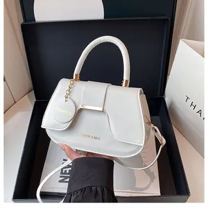 Vue détaillée du sac selle blanc en cuir grainé avec logo métallique doré élégant