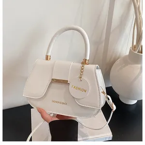 Détail du sac selle blanc avec ferrures dorées et bandoulière amovible sur surface