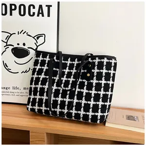 Close-up of black and white checkered tweed tote bag with metal rivet details