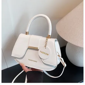 Détail d'un sac selle blanc montrant la quincaillerie dorée et le logo gravé