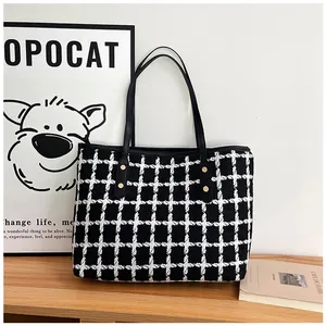 Close-up of black and white checkered tweed tote bag with gold rivet accents and leather trim