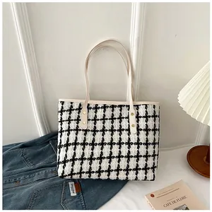 Close-up of black and white striped tweed tote bag with beige leather handles and gold rivets