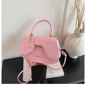 Gros plan du sac selle en cuir rose avec garnitures dorées et breloque mode