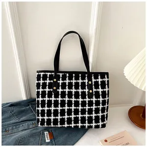 Detail of black and white checkered tote bag with gold rivets and leather handles