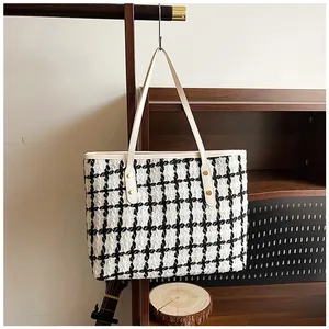 Close-up of black and white striped tweed tote with gold rivets and cream trim details