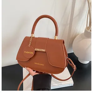 Détail macro du sac selle marron en PU avec boucle dorée et breloque gravée