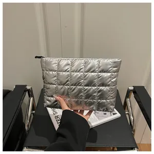 Detailed macro shot of silver metallic quilted cosmetic bag with black zipper closure