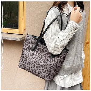Dettaglio di una grande borsa tote leopardata con spalline in pelle nera sottili