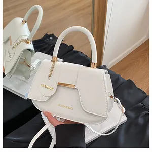 Détail d'un sac selle blanc avec boucle en métal doré et breloques de mode décoratives