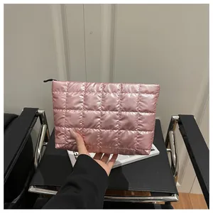 Close-up of pink quilted puffy cosmetic bag featuring square stitching and black zipper