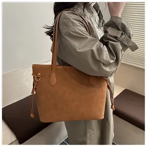 Brown suede tote bag with drawstring details shown on shoulder in aesthetic studio setting