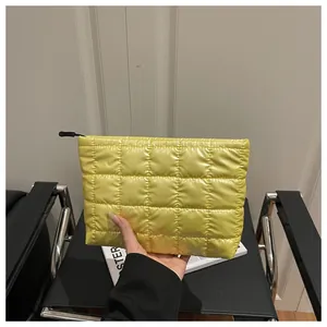 Close-up of bright yellow quilted nylon makeup bag with puffer texture and black zipper