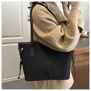 Detail of a black matte leather tote bag with decorative side drawstrings and metal rings