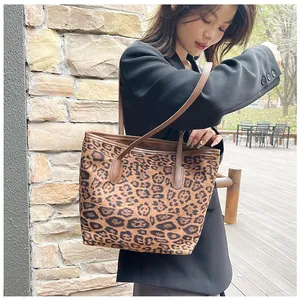 Dettaglio borsa shopper leopardata con manici in pelle marrone e blazer nero elegante