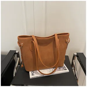 Detailed macro view of caramel suede tote bag with decorative side knot and metal ring