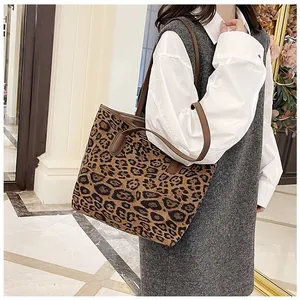 Dettaglio della borsa tote leopardata con cinturini in pelle marrone indossata da un modello
