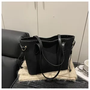 Detail of black tote bag featuring gold hardware rings and side tassel drawstring accents