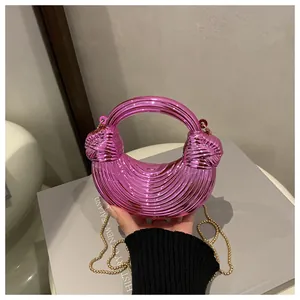 Dettaglio borsa a mezzaluna rosa metallizzato con trama a onde e catena dorata