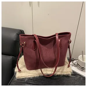 Detail of burgundy suede tote bag featuring side metal buckles and decorative drawstring