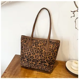 Grande borsa tote leopardata con manici marroni su un tavolo in legno naturale