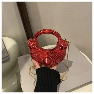Dettaglio borsa rossa metallizzata con design a nodi a spirale e catena dorata