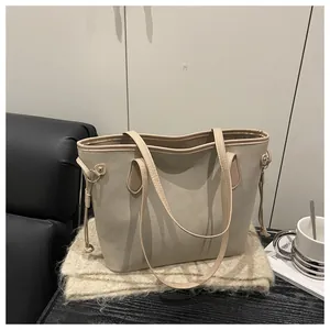 Close-up of beige suede tote bag with drawstring side details and gold hardware