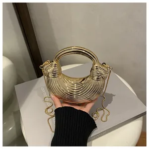 Dettaglio della borsa da sera dorata con texture a pieghe radiali e tracolla a catena