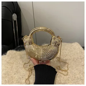 Dettaglio della borsa metallica dorata a semicerchio con texture a onde e manico tondo
