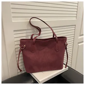 Detail of burgundy suede tote bag featuring side drawstrings and golden ring hardware