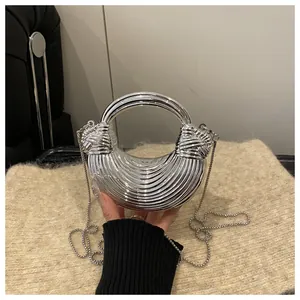 Dettaglio borsa a mezzaluna argento con manico ad anello e trama intrecciata su peluche