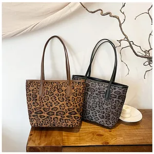 Dettaglio di borse tote leopardate marroni e grigie su un tavolo in legno rustico