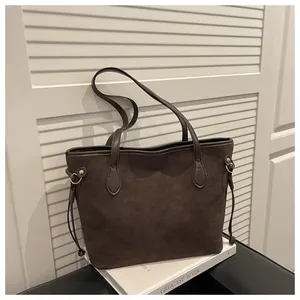 Detail of dark brown suede tote bag with slim drawstrings and gold ring hardware