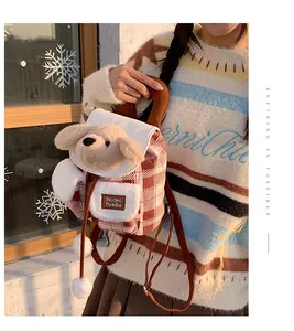 Détail de chiot en peluche sur sac à dos à carreaux rouges avec pompon et poche