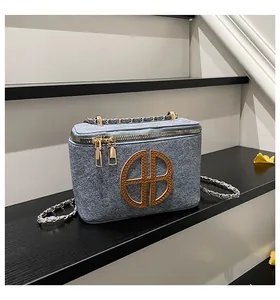 Gros plan du sac en tweed bleu avec logo AB doré sur un support minimaliste