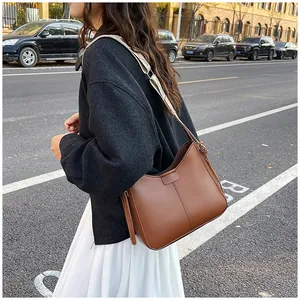 Detail view of caramel leather shoulder bag with wide strap and vertical stitching accents