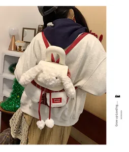 Gros plan du sac à dos lapin en peluche blanc avec bretelles rouges et étiquette