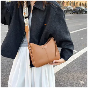 Detail of caramel crossbody bag with ethnic embroidery strap and gold buckles
