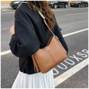 Brown leather crossbody bag detail with wide woven strap and vertical stitching accents
