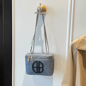 Sac bandoulière gris texturé avec chaîne dorée et logo B circulaire au design élégant