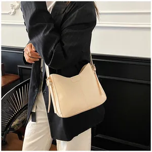 Chic cream leather shoulder bag with gold buckle on a model in minimalist interior