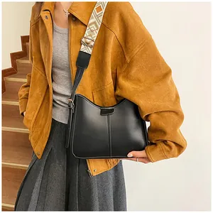 Detail of a black leather half-moon crossbody bag with geometric pattern wide strap