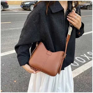 Detailed view of caramel leather saddle bag with geometric patterned woven wide strap
