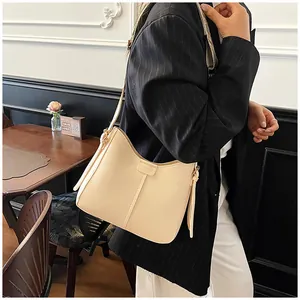 Detail of minimalist beige hobo bag with wide shoulder strap and vertical stitching