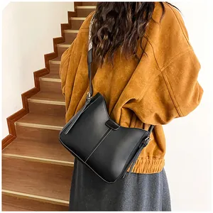 Detail of black hobo bag with silk scarf strap worn over a brown corduroy jacket